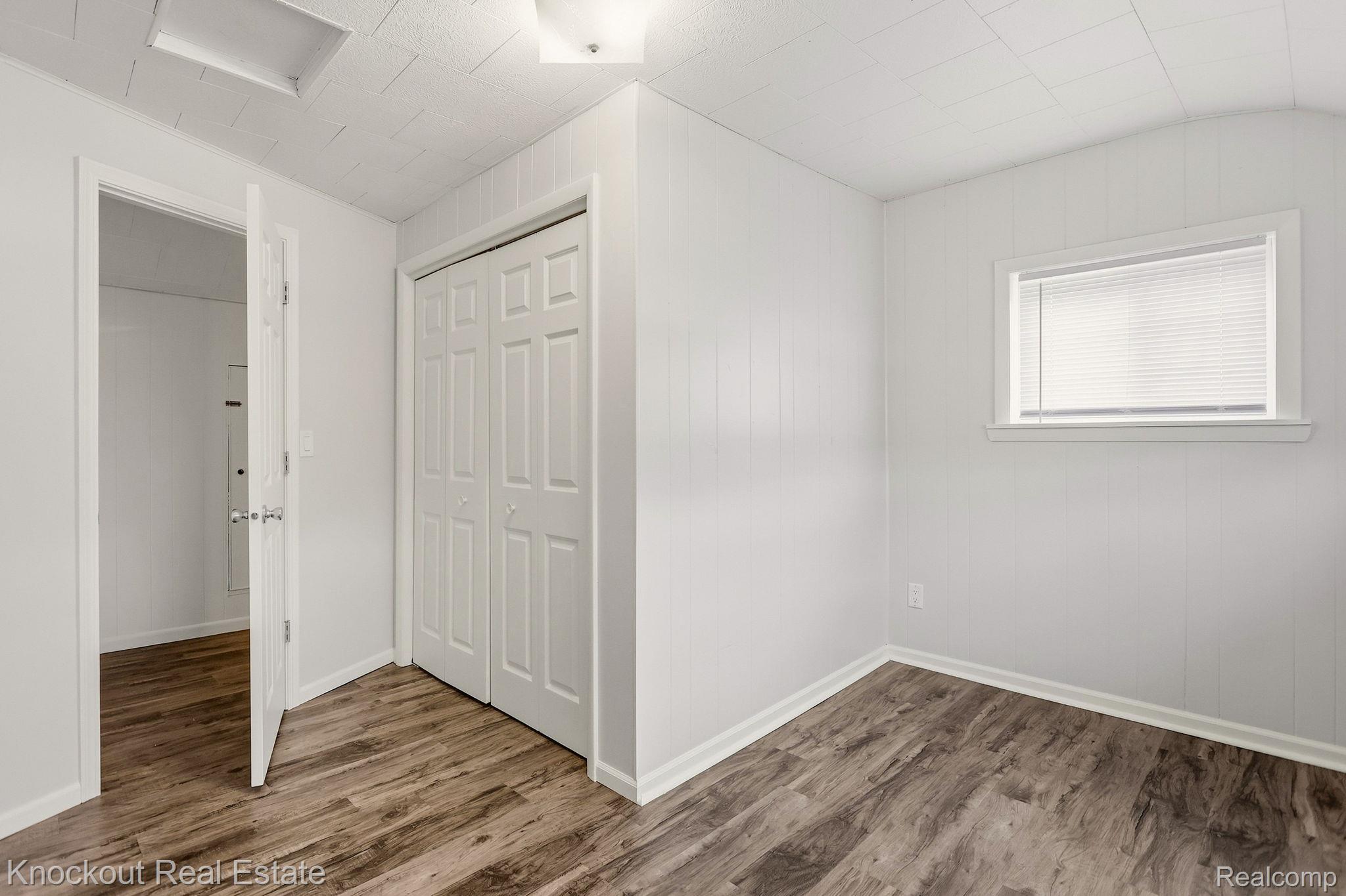 8771 Van Cleve Road Vassar, MI 48768 - Photo 24 of 44 Wood-finish flooring, white paneling, white bi-fold closet doors, and a window with blinds