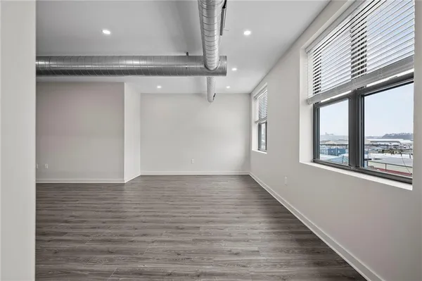 a view of an empty room with a window and wooden floor