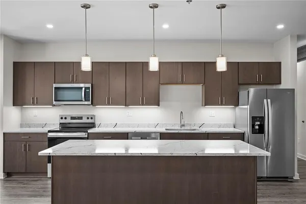 a kitchen with kitchen island a refrigerator a sink a stove a microwave and wooden cabinets