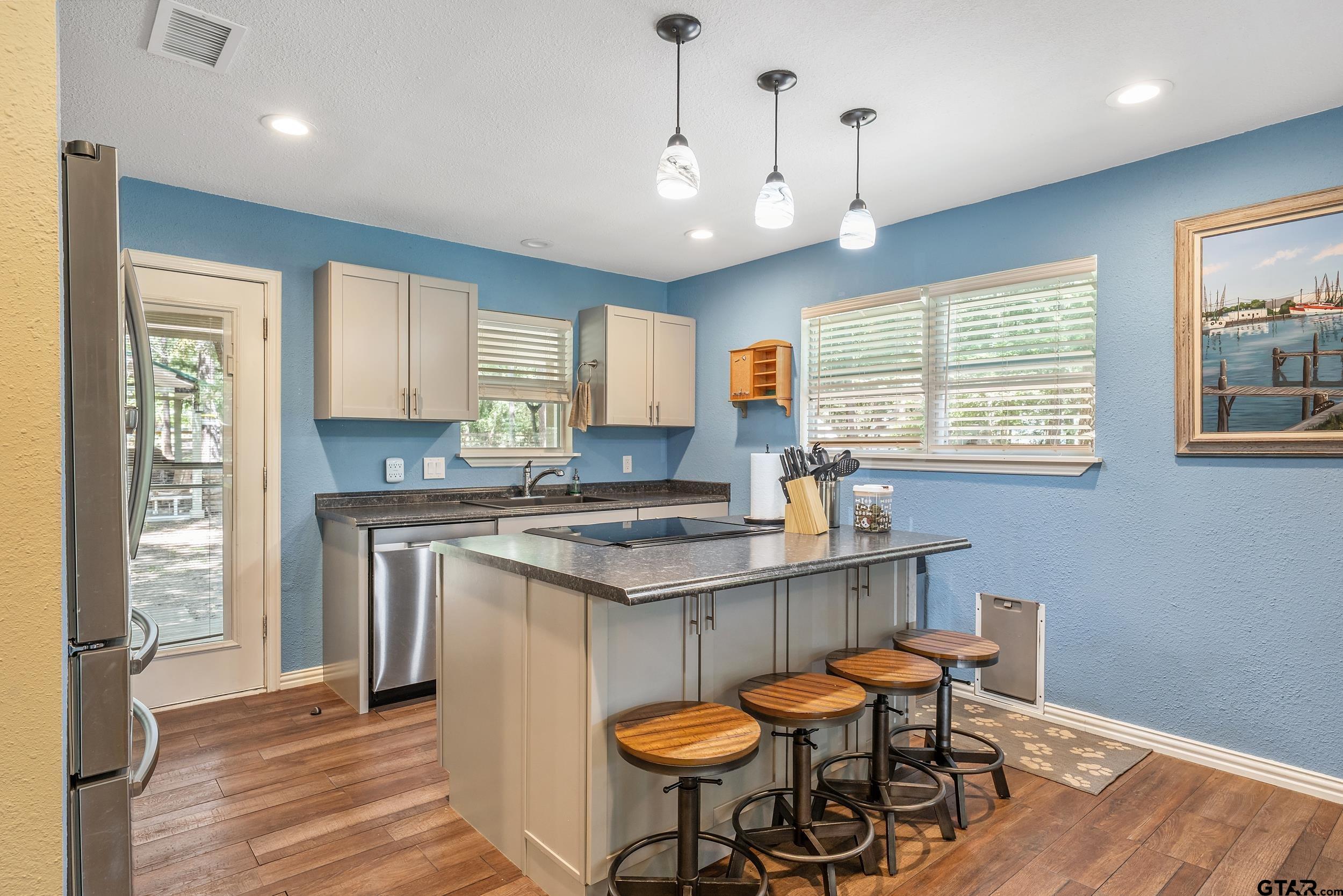 230 Deborah Street Bullard, TX 75757 - Photo 6 of 23 a kitchen with stainless steel appliances granite countertop a stove a sink dishwasher a dining table and chairs with wooden floor