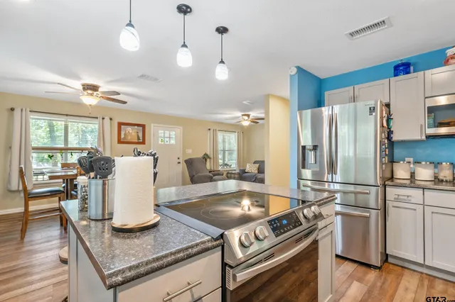 a kitchen with stainless steel appliances granite countertop a stove refrigerator and chairs