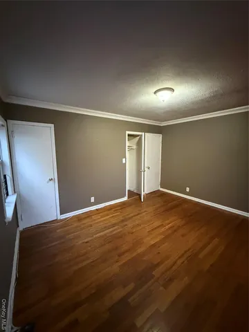 a view of an empty room with window and wooden floor