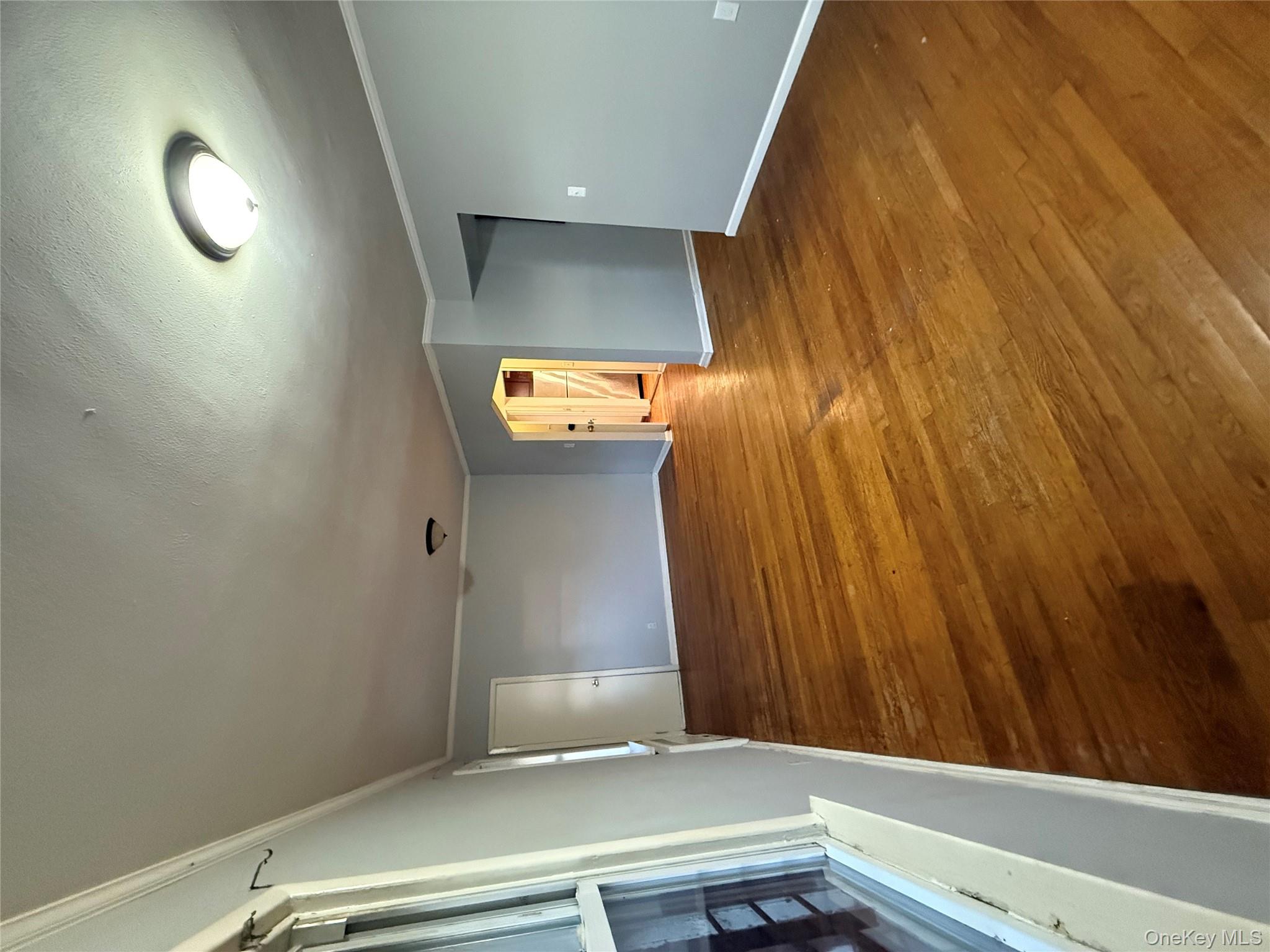 109-11 225th Street, Unit 2 Queens, NY 11429 - Photo 8 of 13 wooden floor in an empty room with a fireplace