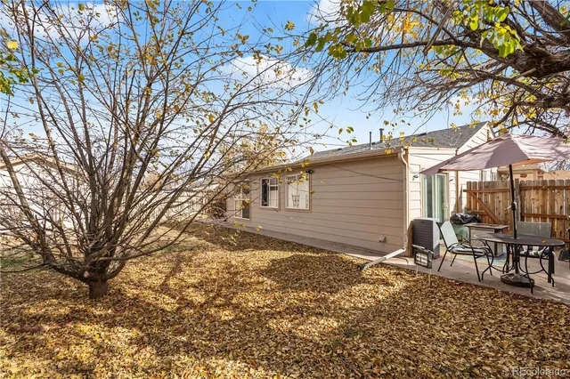 a backyard of a house with table and chairs under an umbrella