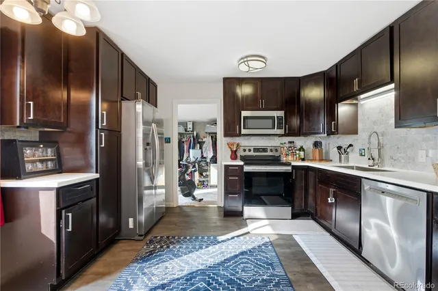 a kitchen with stainless steel appliances granite countertop a refrigerator a stove and a sink with wooden floor