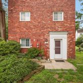 front view of a brick house with a yard and plants