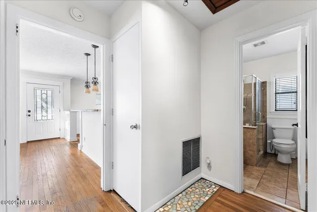 a view of a hallway with bathroom and wooden floor
