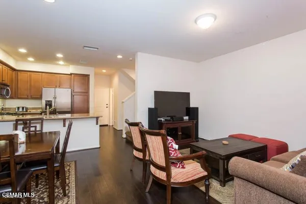 a living room with furniture a flat screen tv and kitchen view