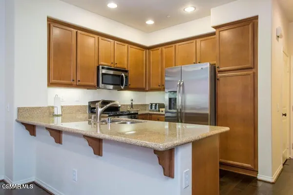 a kitchen with stainless steel appliances granite countertop a refrigerator a sink a stove a microwave and island