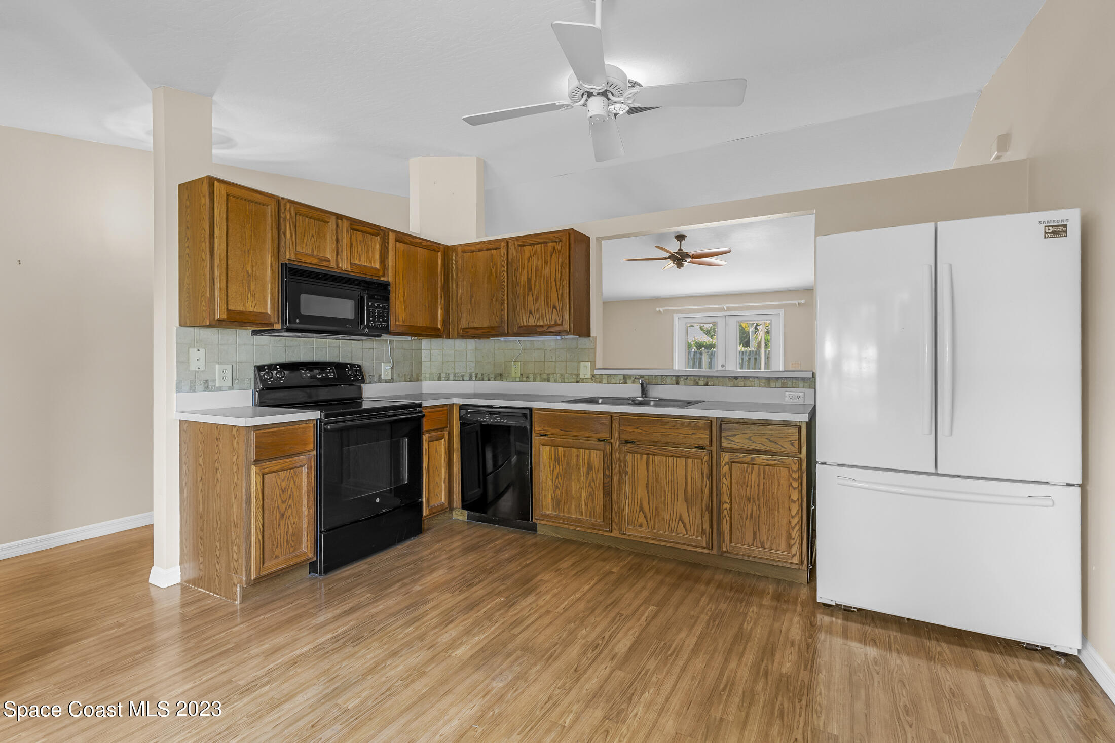 813 Cebu Place Melbourne, FL 32940 - Photo 4 of 25 a kitchen with stainless steel appliances granite countertop a refrigerator a stove top oven a sink and dishwasher with wooden floor