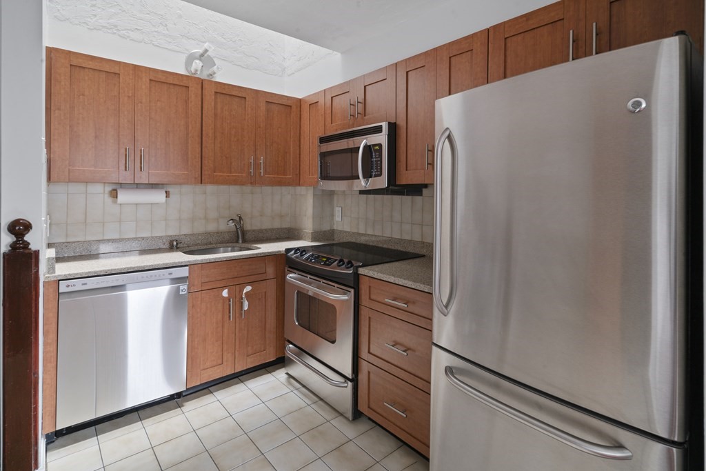 a kitchen with stainless steel appliances granite countertop a refrigerator sink and stove