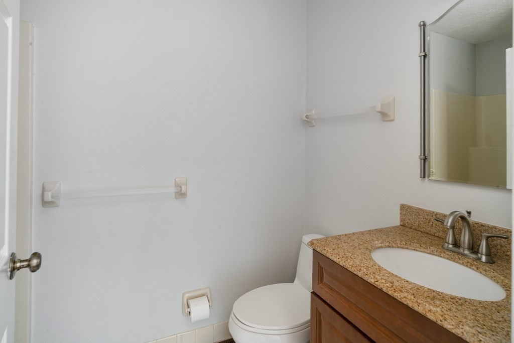 68 Regent Circle, Unit 68 Brookline, MA 02445 - Photo 11 of 21 a bathroom with a granite countertop toilet a sink and a mirror