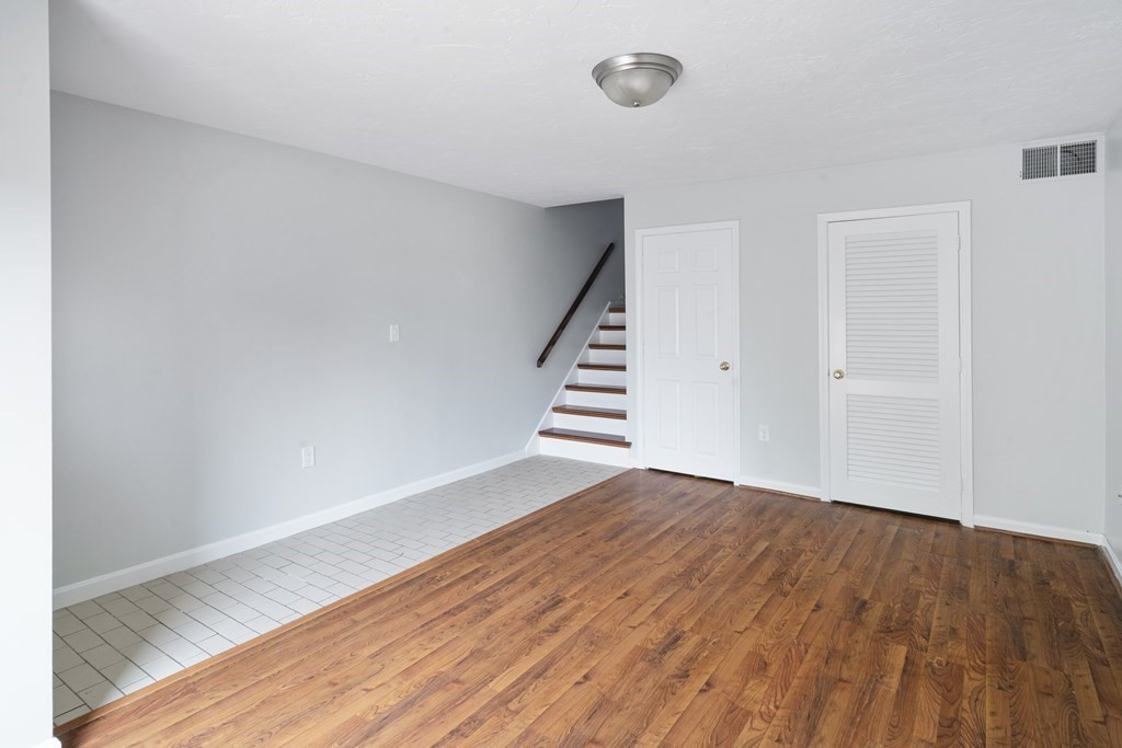 68 Regent Circle, Unit 68 Brookline, MA 02445 - Photo 6 of 21 a view of an empty room with wooden floor and stairs