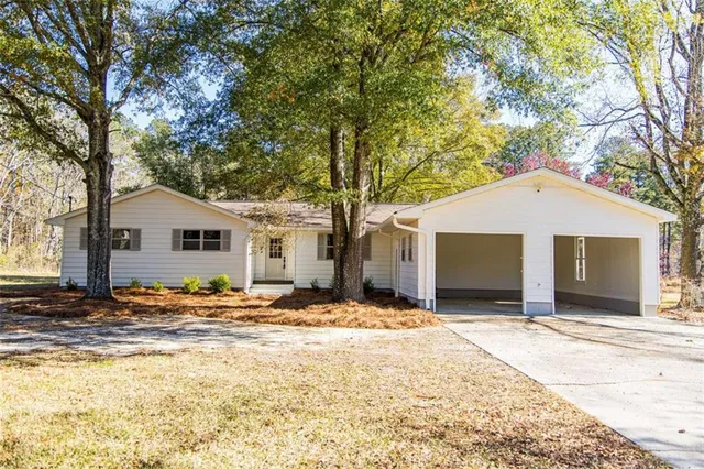 a backyard of a house with large trees and wooden fence