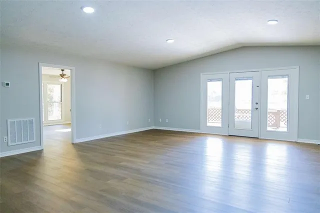a view of an empty room with wooden floor and a window