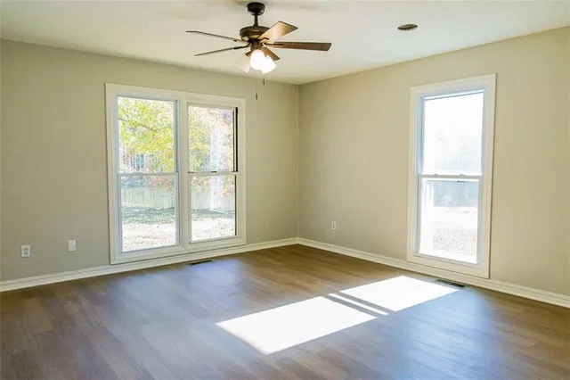 a view of an empty room with wooden floor and a window