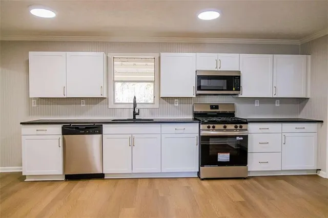 a kitchen with granite countertop a stove a sink and a microwave