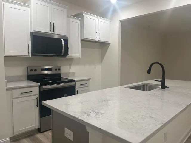 a kitchen with a sink and a stove top oven with wooden floor