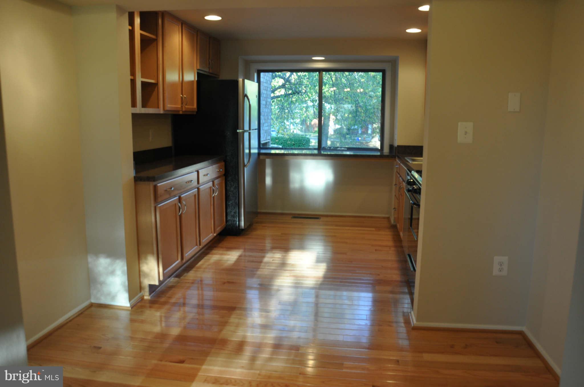 9415 Merryrest Road Columbia, MD 21045 - Photo 7 of 17 a kitchen with granite countertop white cabinets and wooden floor