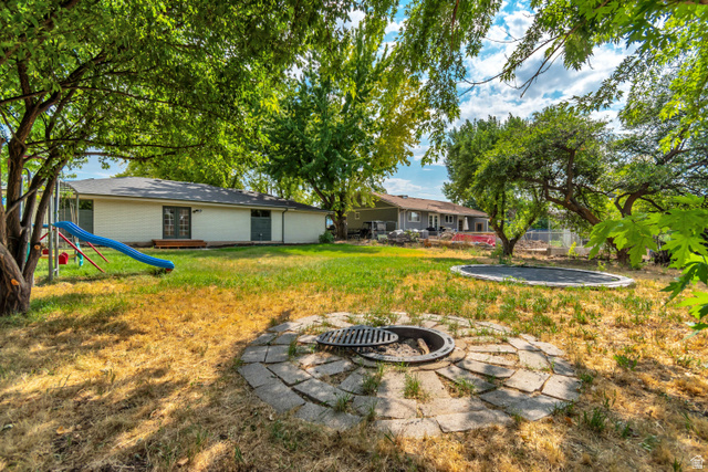 1010 West Maple Street Mapleton, UT 84664 - Photo 21 of 24 Expansive backyard featuring mature trees, a stone-paved fire pit area, and ample space