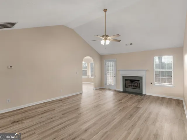a view of an empty room with wooden floor fireplace and a window