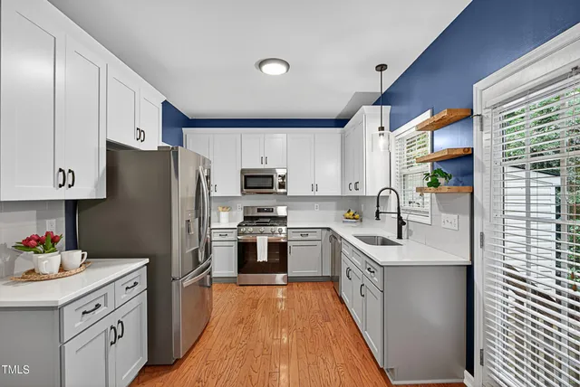 a kitchen with stainless steel appliances granite countertop a refrigerator a sink dishwasher a oven with white cabinets and wooden floor