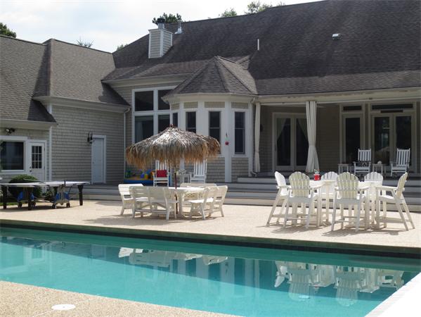 a front view of a house with swimming pool and furniture