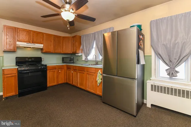 a kitchen with stainless steel appliances granite countertop a refrigerator a sink dishwasher a stove and a dining table with wooden floor