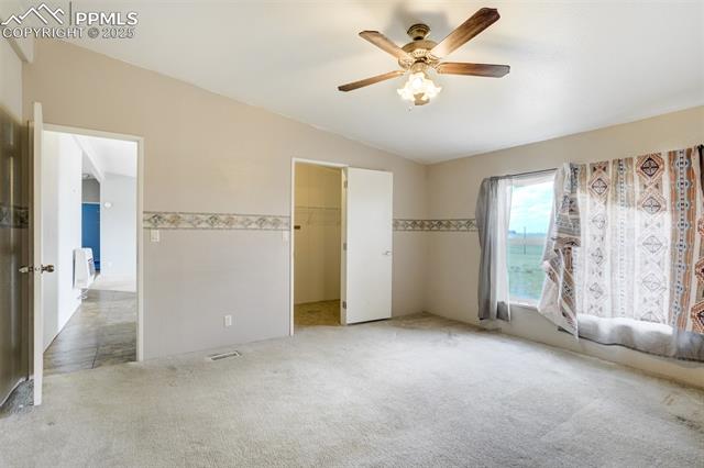 1435 Equestrian Point Yoder, CO 80864 - Photo 20 of 49 Unfurnished bedroom with light carpet, lofted ceiling, a walk in closet, a ceiling fan, and a closet