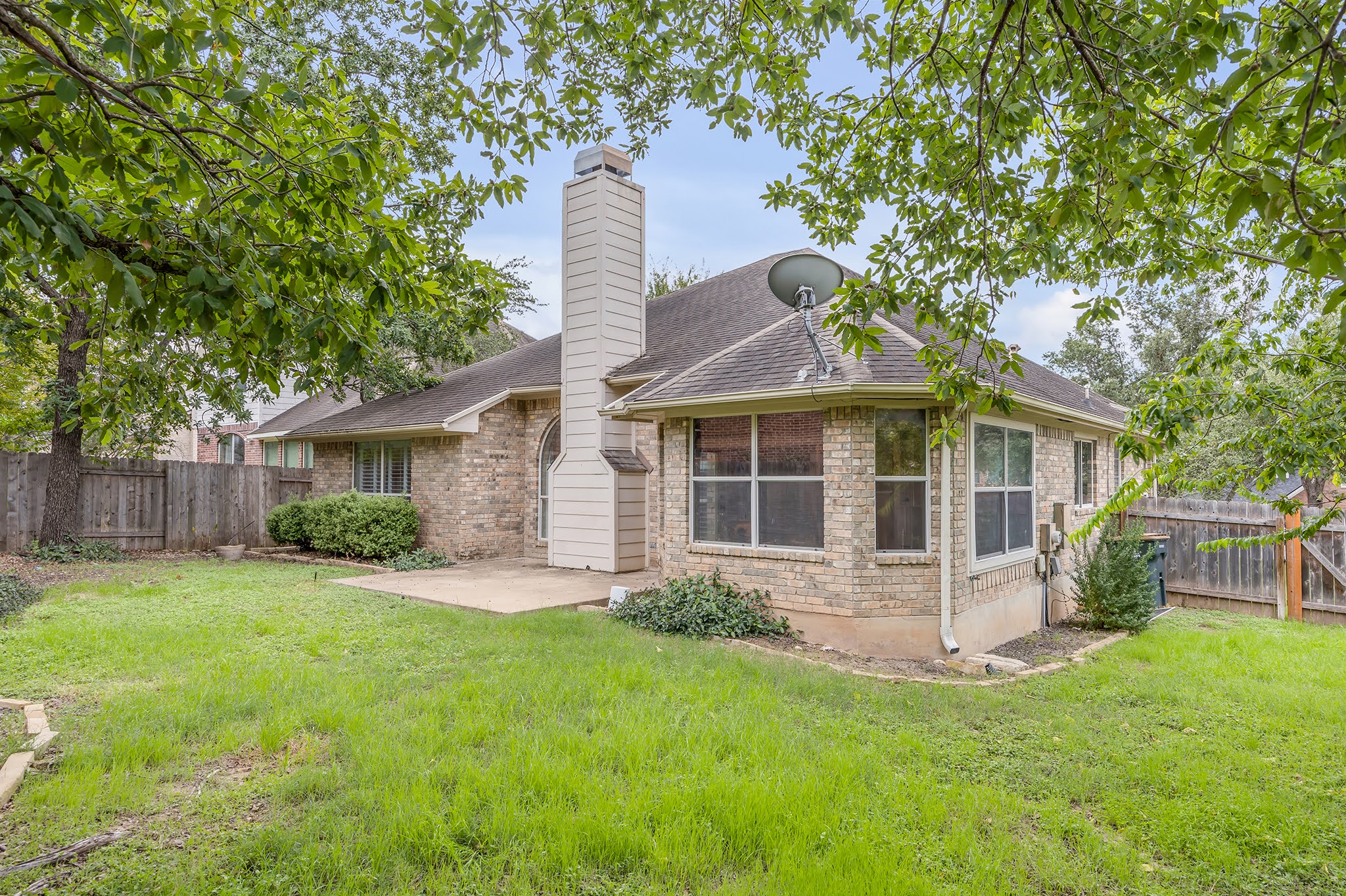 2726 Grimes Ranch Road Austin, TX 78732 - Photo 33 of 35 Rear view of house featuring a fenced backyard, a patio area, a chimney, brick siding, and roof with shingles