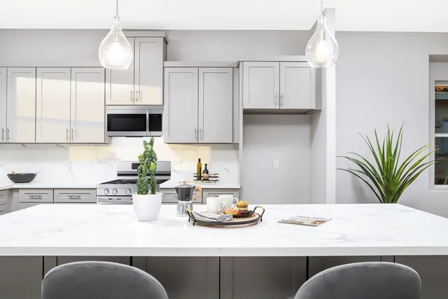 a kitchen with kitchen island granite countertop a sink a stove white cabinets and a granite counter tops