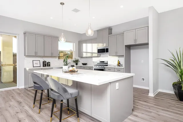 a kitchen with stainless steel appliances a white table chairs refrigerator and cabinets