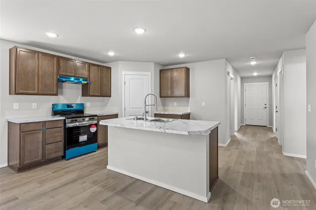 a kitchen with stainless steel appliances granite countertop a stove top oven a sink a refrigerator and a granite counter tops with white cabinets