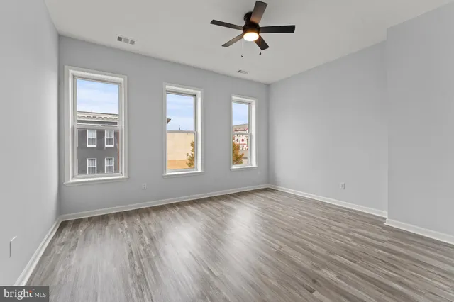 a view of empty room with wooden floor and fan
