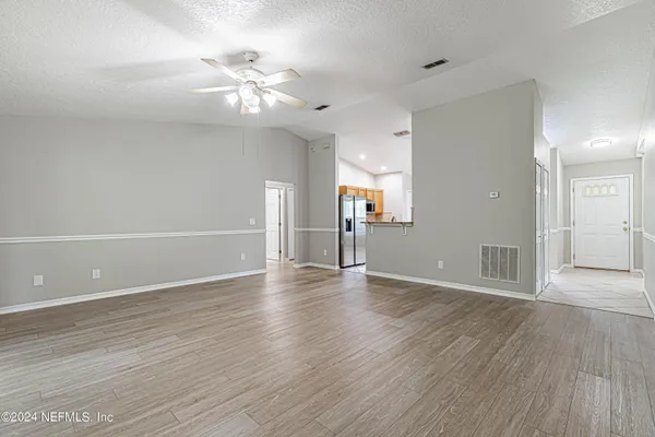 a view of an empty room with wooden floor and a ceiling fan