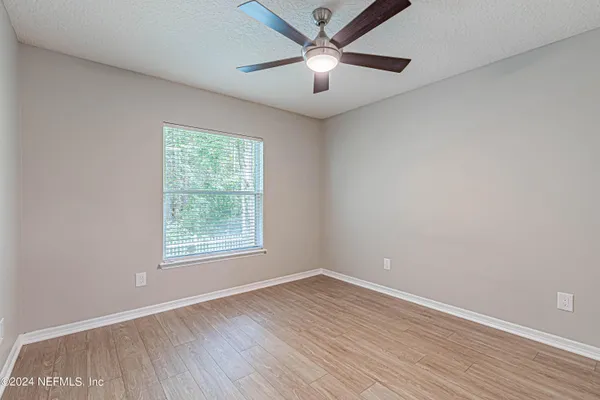 an empty room with wooden floor ceiling fan and windows