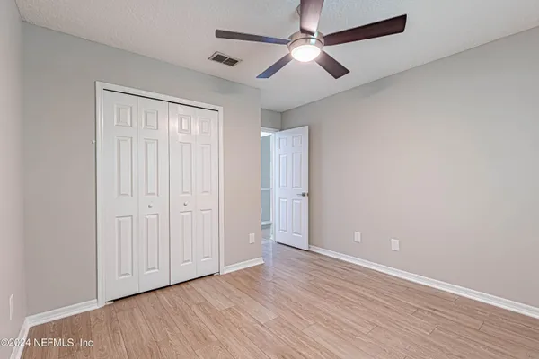 an empty room with wooden floor ceiling fan and windows