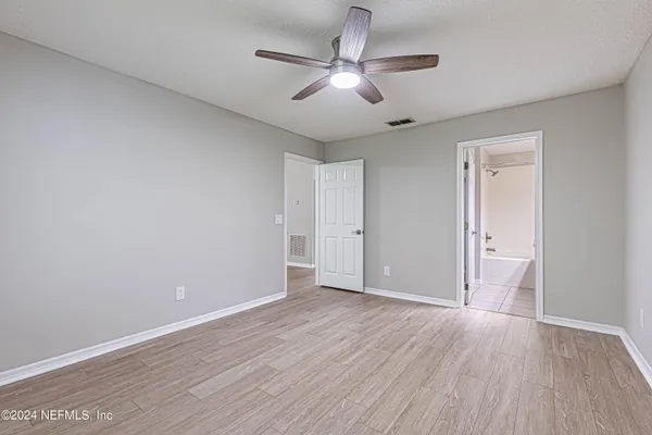 an empty room with wooden floor and ceiling fan