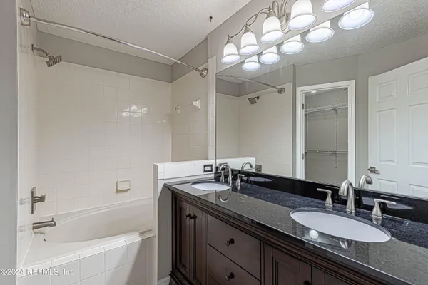 a bathroom with a granite countertop sink mirror and a bathtub
