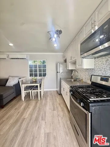 a kitchen with stainless steel appliances a stove a sink dishwasher and a dining table with wooden floor