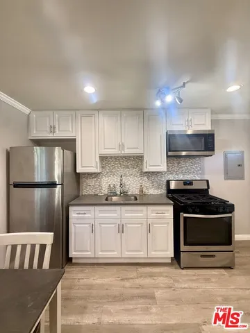 a kitchen with granite countertop a refrigerator stove top oven and sink