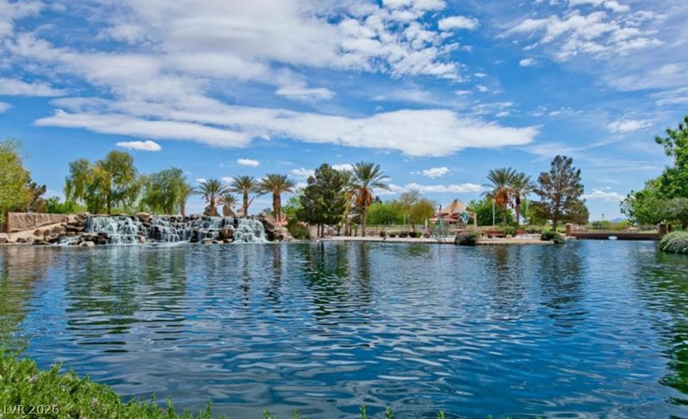 6405 North Raptor Court North Las Vegas, NV 89084 - Photo 65 of 66 A tranquil lake with a cascading waterfall creates a peaceful outdoor oasis under a clear sky.