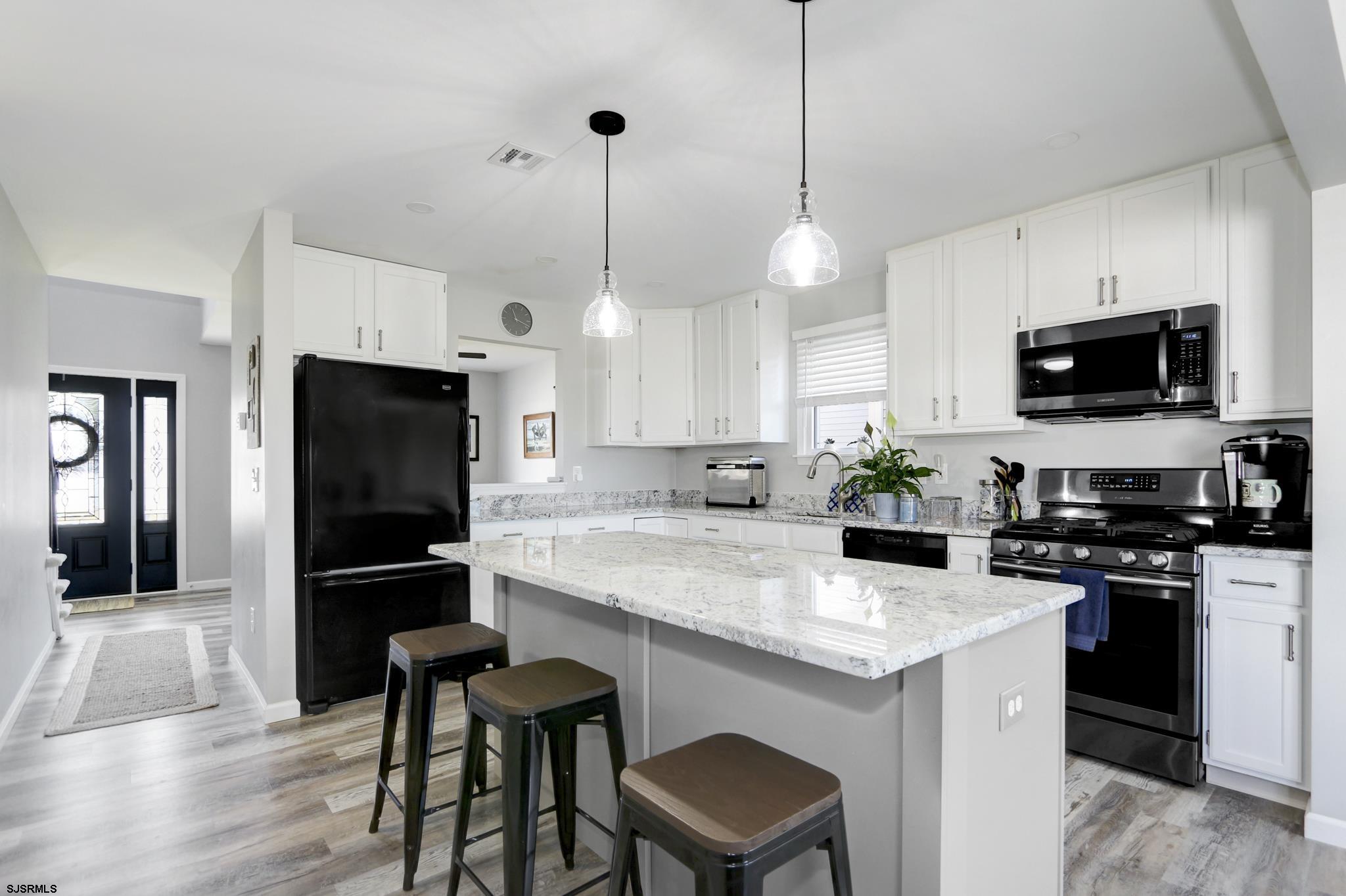 218 Hagen Road Brigantine, NJ 08203 - Photo 5 of 32 a kitchen with kitchen island a refrigerator a stove a counter space and wooden floor