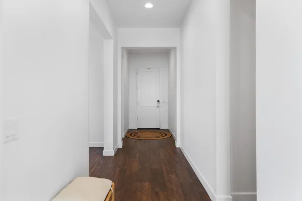 a view of a hallway with toilet and a wooden floor