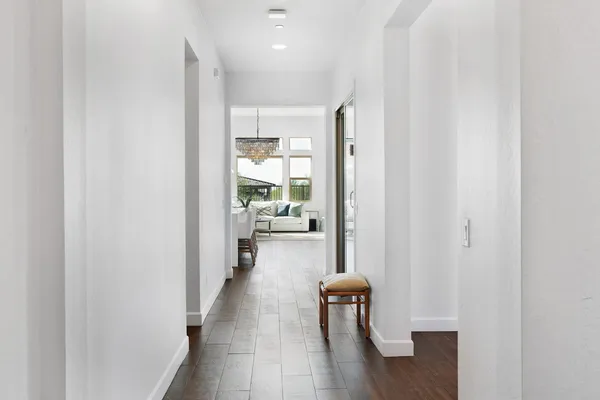 a hallway with wooden floor a glass table and chairs
