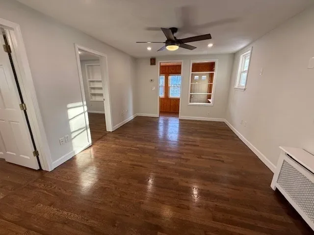 a view of an empty room with window and wooden floor