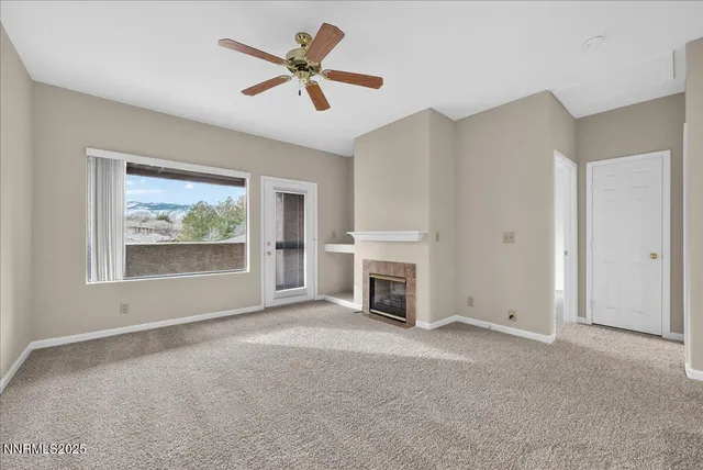 an empty room with windows fireplace and fan