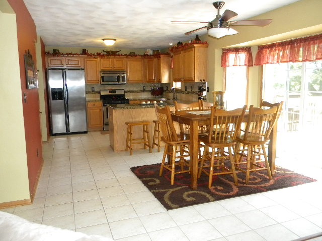 10745 Chicory Ridge Way Roscoe, IL 61073 - Photo 6 of 25 a kitchen with stainless steel appliances kitchen island granite countertop a refrigerator a stove a microwave oven with a dining table and chairs