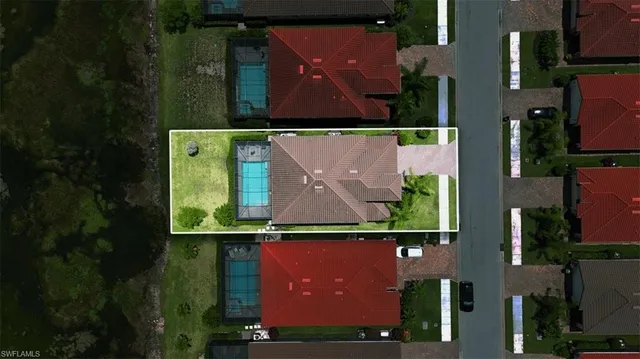 a view of a swimming pool with lawn chairs potted plants and palm trees