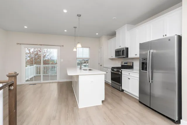 a kitchen with a refrigerator a stove top oven a sink dishwasher and white cabinets with wooden floor